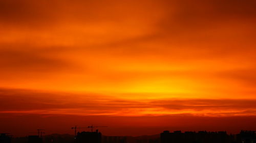 Low angle view of silhouette buildings against orange sky