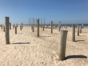 Wooden posts on beach against clear sky