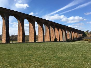 Arch bridge on field against sky