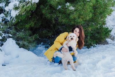 Woman with dog on snowcapped mountain against sky