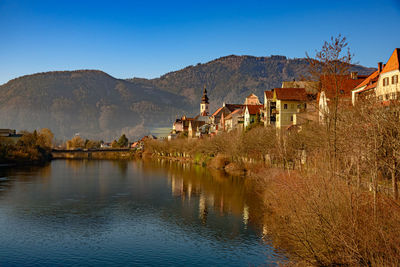 Houses by river and buildings against clear sky in frohnleiten in austria