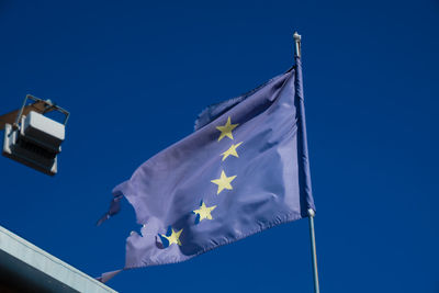 Low angle view of flag against blue sky