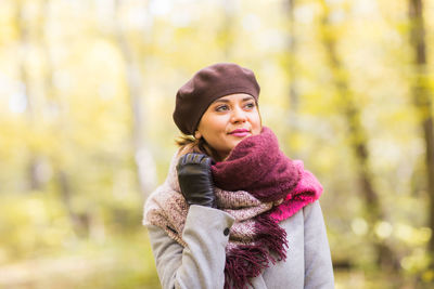 Portrait of young woman standing in forest during winter