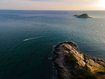 The aerial view of seashore and cruise driving on the blue sea with sunset background