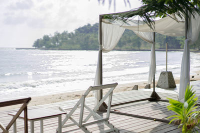 Chairs on beach by sea against sky