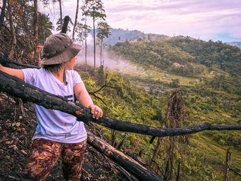 Man wearing hat standing by tree against sky