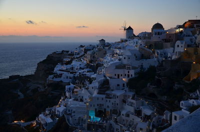 High angle view of city by sea against sky during sunset