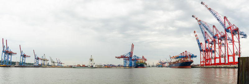 Cranes at commercial dock against sky