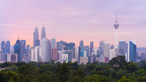 Modern buildings in city against sky during sunset