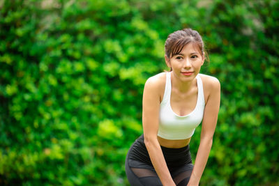 Portrait of young woman standing against blurred background