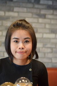 Portrait of beautiful young woman sitting at wooden table in cafe