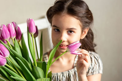 Portrait of a beautiful romantic little girl with a bouquet of purple tulips
