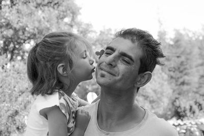 Close-up of daughter kissing father while standing outdoors