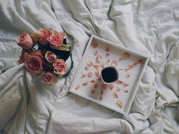 High angle view of black tea along with roses on wrinkled sheet