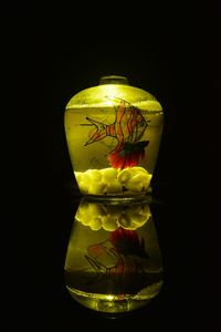 Close-up of lit candles on glass against black background