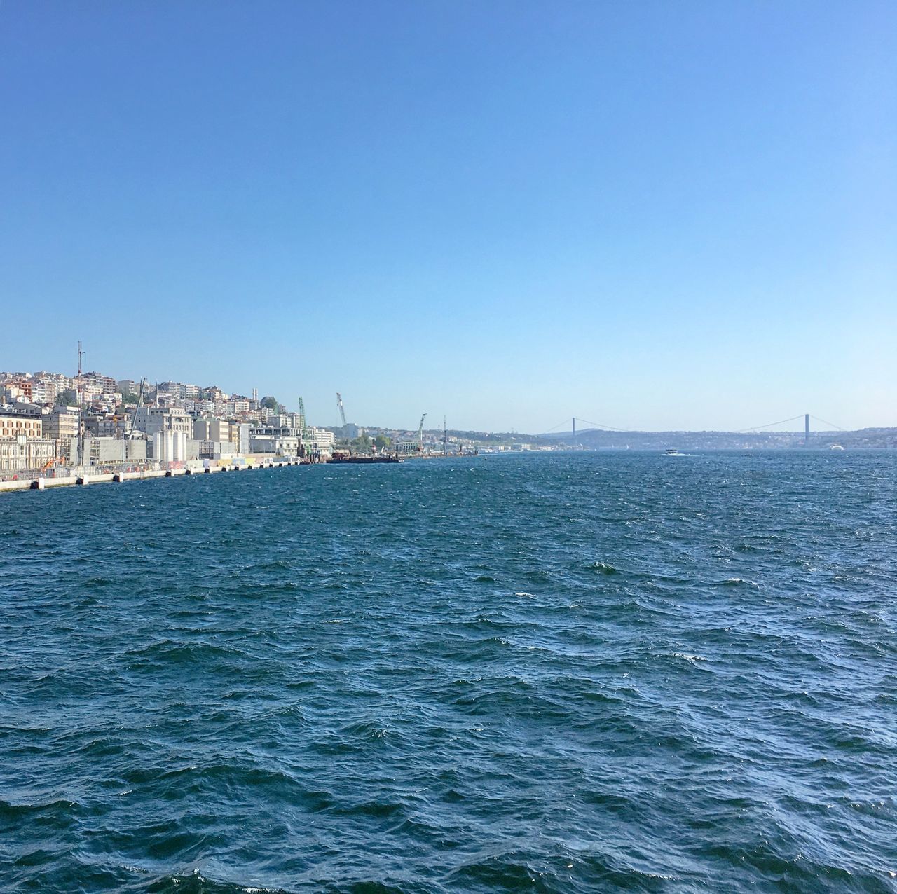 SCENIC VIEW OF SEA BY CITY AGAINST CLEAR BLUE SKY