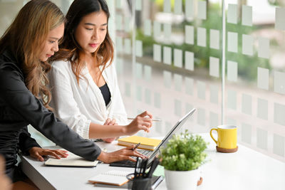 Businesswoman using mobile phone while sitting on table