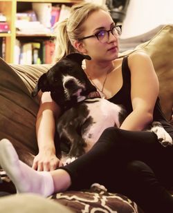 Young woman with dog sitting on sofa at home