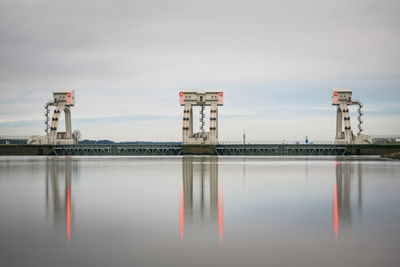 View of factory by lake against sky