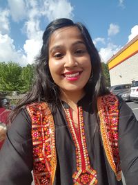 Portrait of smiling young woman against sky