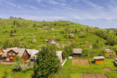 Houses on green landscape against sky