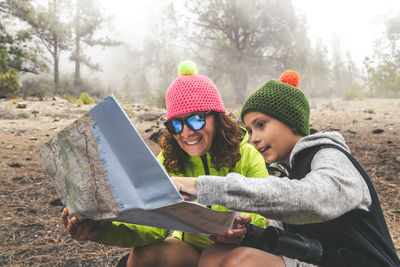 Woman with son reading map at forest