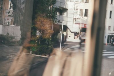 Road by buildings seen through glass window