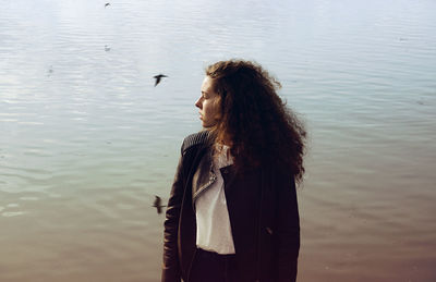 Woman wearing leather jacket while standing by lake