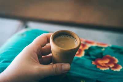 Close-up of cropped hand holding coffee in clay cup