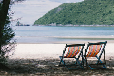 Chairs on beach against mountain