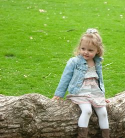 Cute girl sitting on fallen tree at park