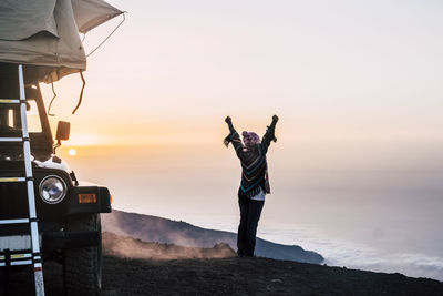 Man photographing at sea shore against sky during sunset