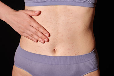 Midsection of woman standing against black background