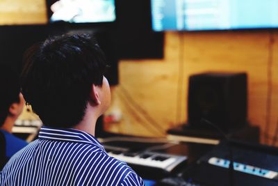 Rear view of man sitting in recording studio