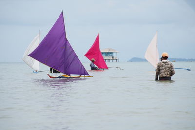 People in boat sailing on sea against sky