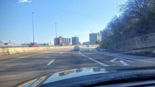 Cars on road against cloudy sky