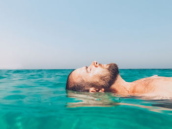 Portrait of man swimming in sea against sky