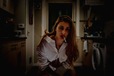 Beautiful woman smoking cigarette in kitchen