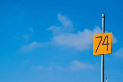 Low angle view of road sign against blue sky