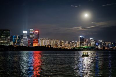 Illuminated urban skyline against sky at night