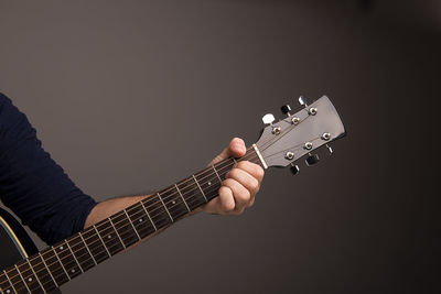 Cropped image of musician playing guitar against gray background