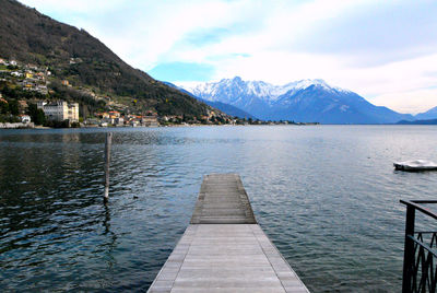 Pier over lake by mountains against sky