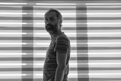 Self portrait of photographer man standing against wall at home