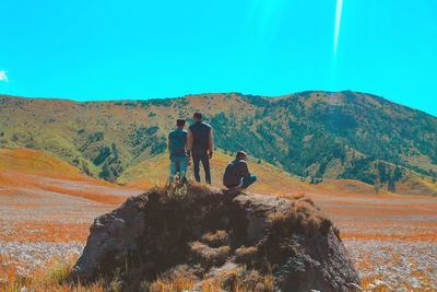 Rear view of men on mountain against sky