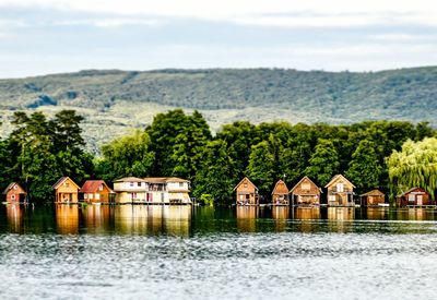 Houses by lake and buildings against sky