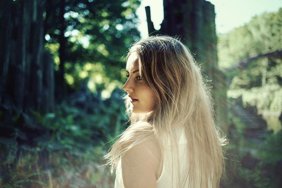 focus on foreground, long hair, young adult, young women, headshot, person, lifestyles, brown hair, leisure activity, looking away, tree, close-up, head and shoulders, contemplation, blond hair, medium-length hair, human hair