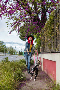 Woman running with dogs on footpath near fence