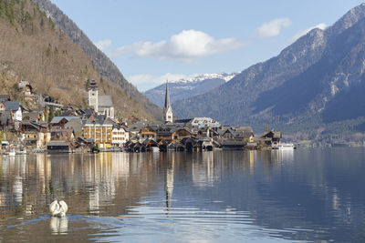 Sailboats in lake by buildings against sky