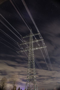 Low angle view of electricity pylon against sky at night