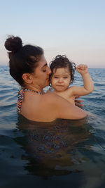 Portrait of daughter with mother in sea against sky